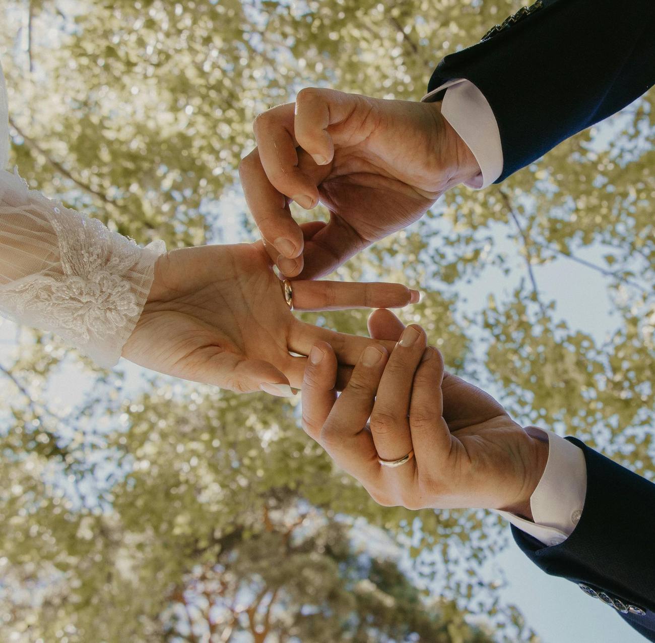 Pareja uniendo sus manos con las alianzas de boda