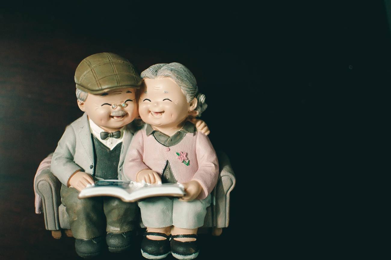Figuras de una pareja de ancianos leyendo un libro