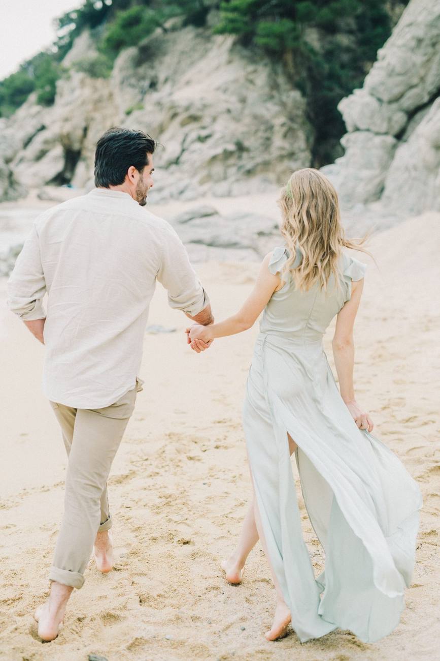 Pareja caminando descalza por la playa